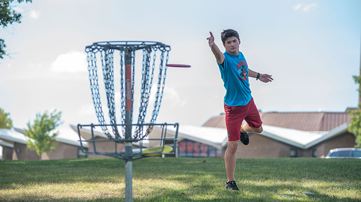 Student playing disc golf on campus